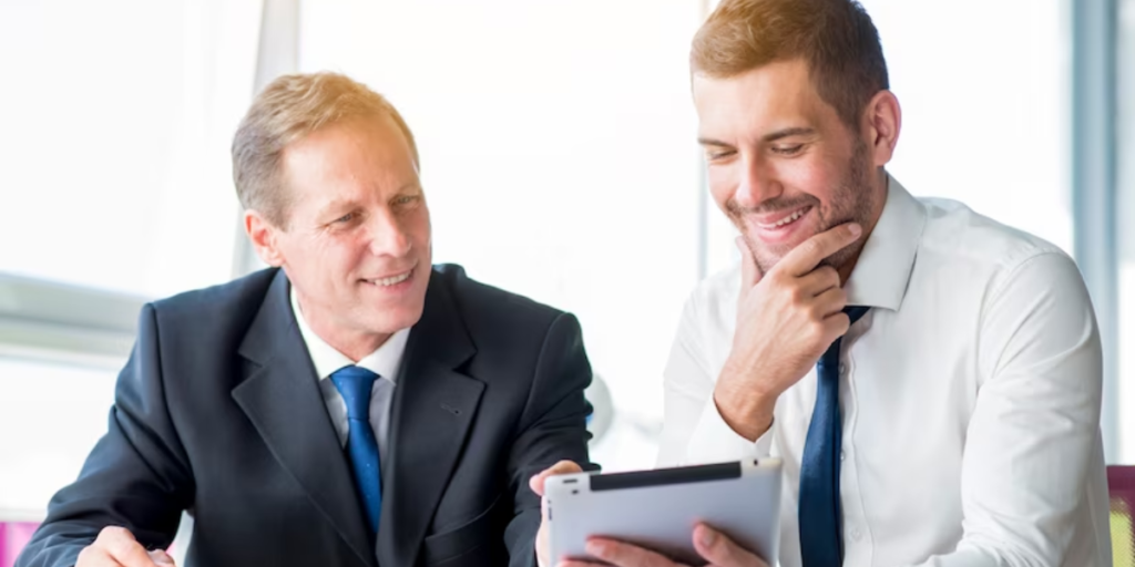 A boss with an effective plan design and his male employee are happy as they look over a tablet