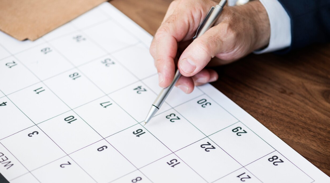 A hand of a business man holding a pen as he circles a date on a calendar to ensure he meets ERISA deadlines.