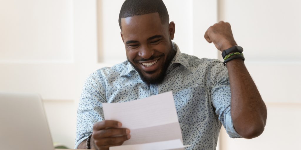 Man smiling and fist pumping air as he looks at 401(k) approval document