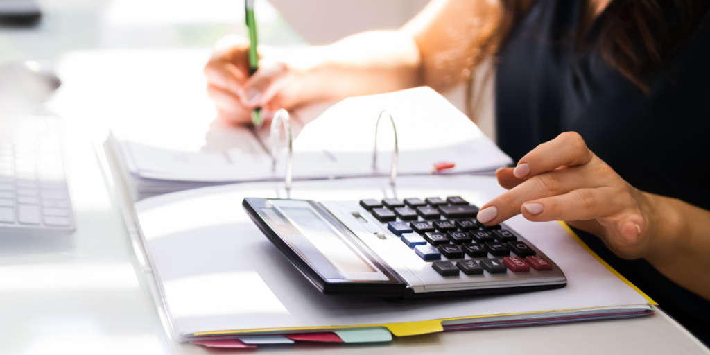 woman using calculator and writing in binder