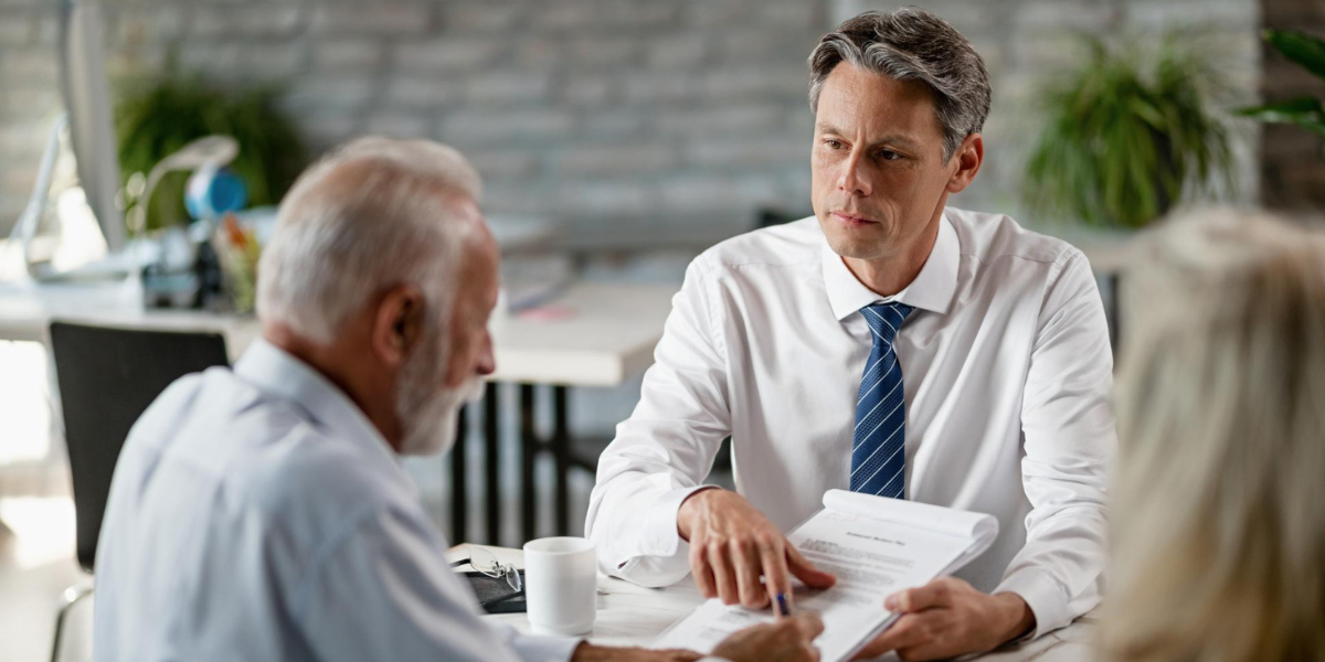 Advisor showing retirement plan documents to elderly couple