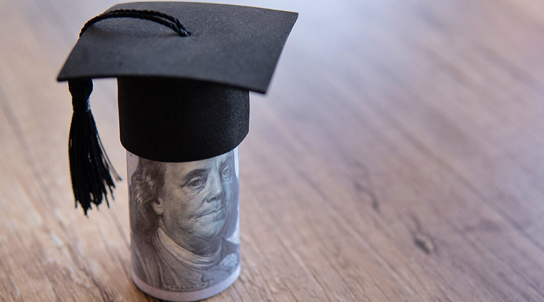 Closeup image of graduation cap and money on table.